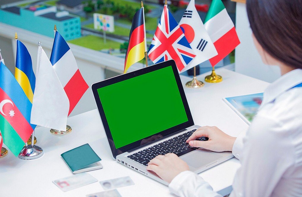 translator working on a laptop in front of several flags