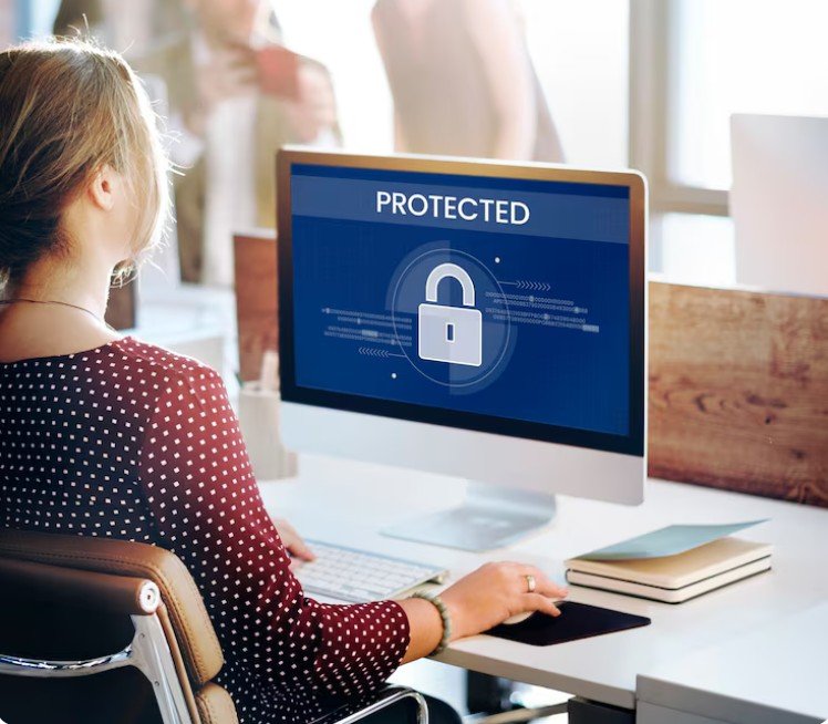 a woman working on a pc with the monitor showing the word protected