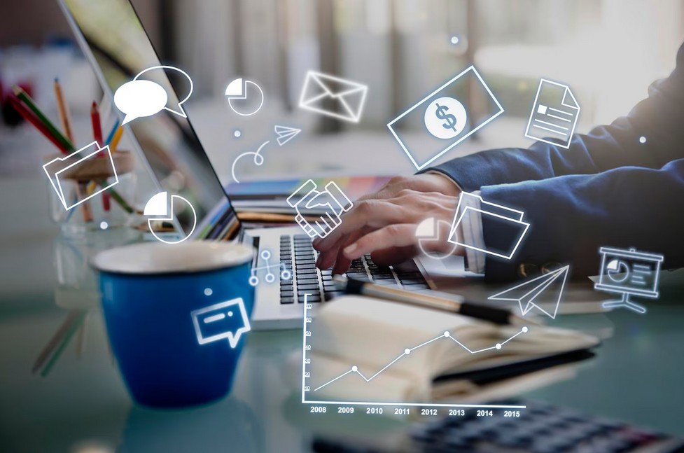 a man working on a laptop with some digital icons appear on a virtual monitor